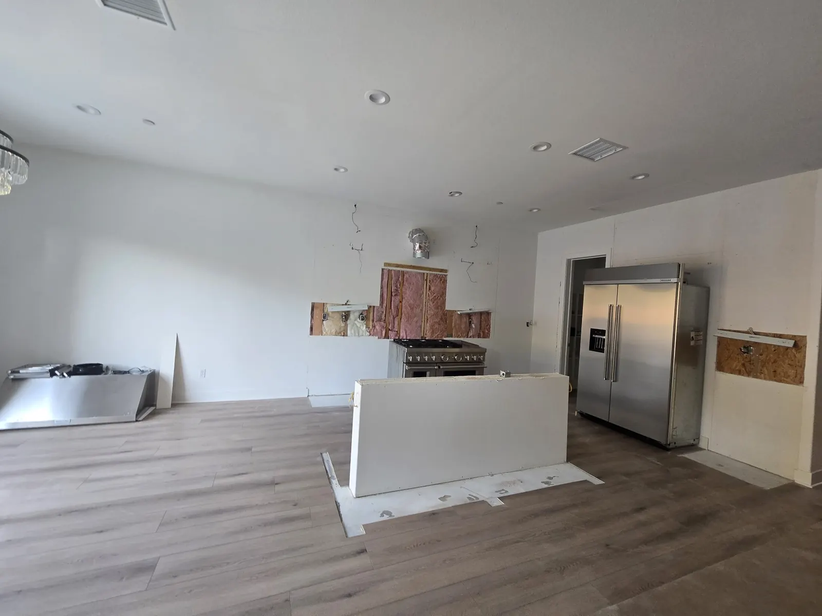 The same kitchen after removal: cabinets gone, bare walls, debris hauled away, only the range and refrigerator left in place